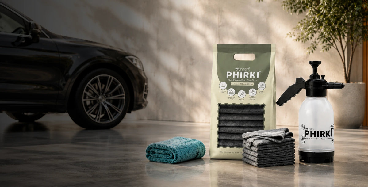PHIRKI Car cleaning products including a 2L foam sprayer and microfiber cloths on a reflective surface with a car in the background.